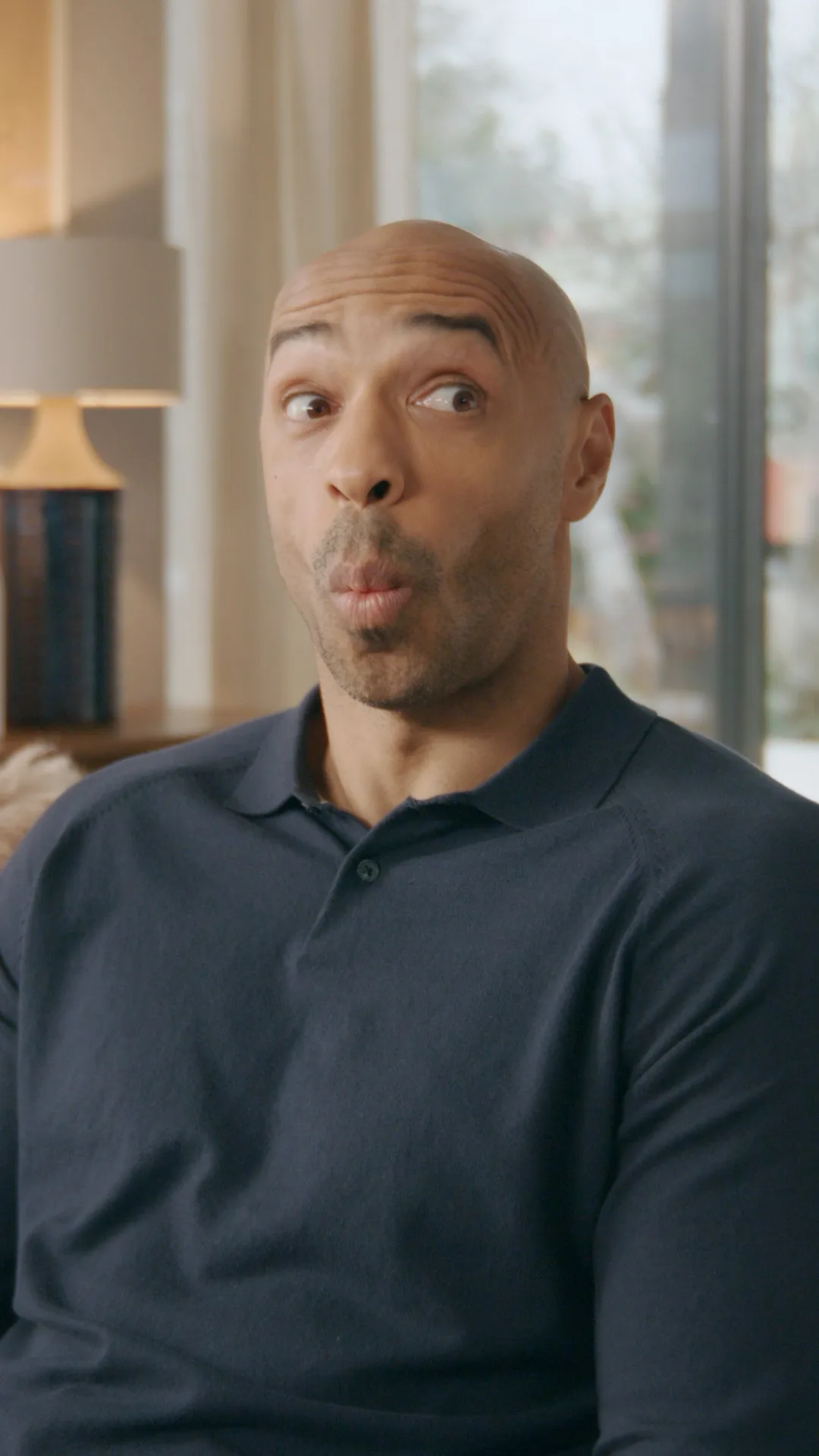 Thierry Henry reacting in surprise while watching TV